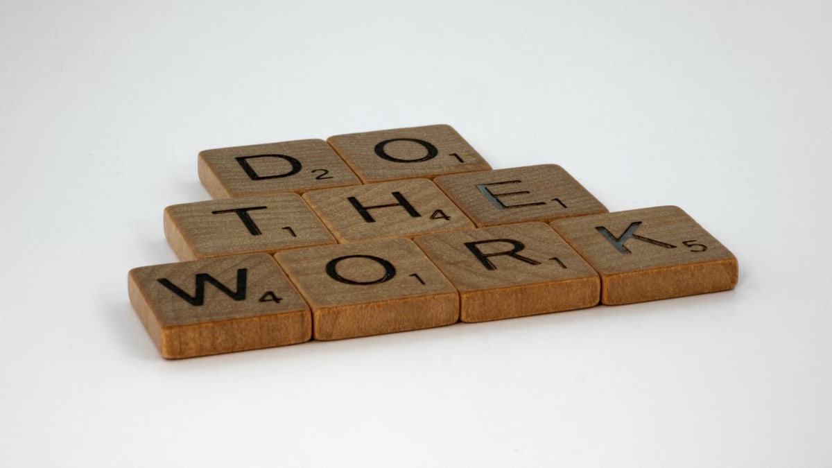Motivational message spelled out with scrabble tiles on white background.